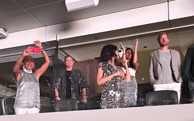 Prince Harry and Meghan Markle were pictured in the crowd at SoFi Stadium in Los Angeles on Friday night.  Pictured: Harry (right), Meghan (second right) and her mother Doria Ragland (left)