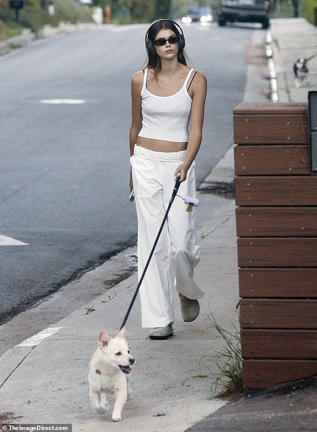 Rocking big headphones: The 22-year-old Malibu native showed off her toned stomach in a white cropped tank top, matching wide-leg pants and $158 gray Birkenstock 'Boston Soft Footbed' clogs