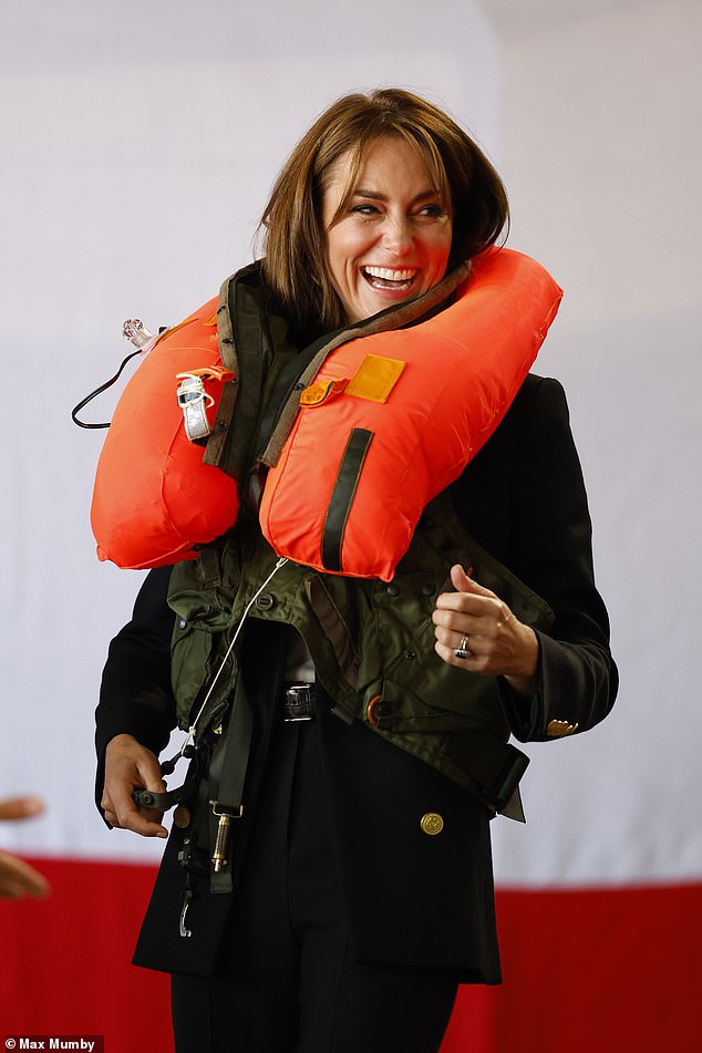 The princess couldn't help giggling as she inflated a life jacket while visiting a hangar on the base