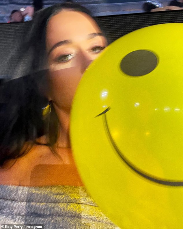 Loving life: She posed with a smiley balloon while watching the show with a group of friends