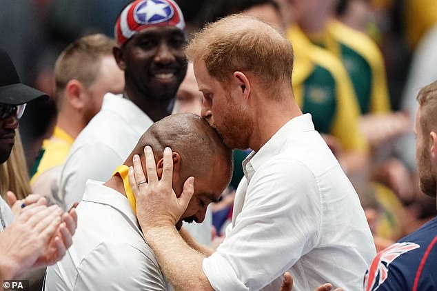 Prince Harry kisses Team USA's Davey Martinez on the head as he presents the team with gold medals after their victory over Team UK in the wheelchair rugby final last night