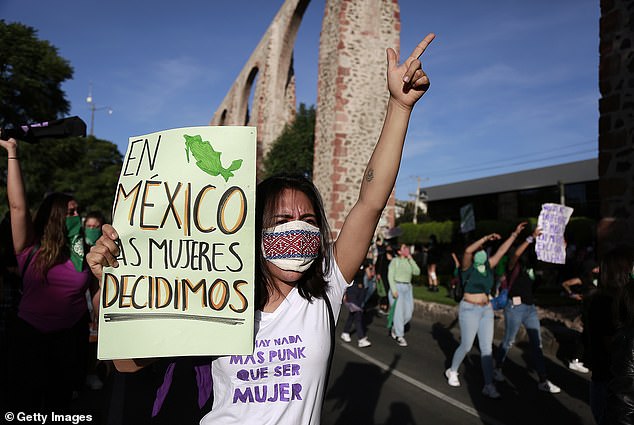 A woman holds up a sign that reads, 