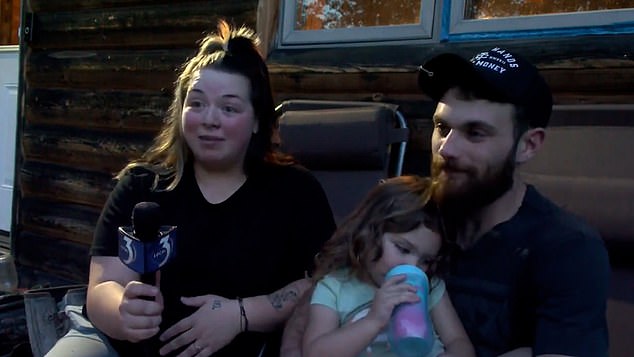 Thea, from the rural town of Faithorn in Michigan's Upper Peninsula, decided to go on an adventure Wednesday after her mother Brooke turned her back.  Pictured: Thea with her father Alex and mother Brooke after she was found in the woods with her two dogs