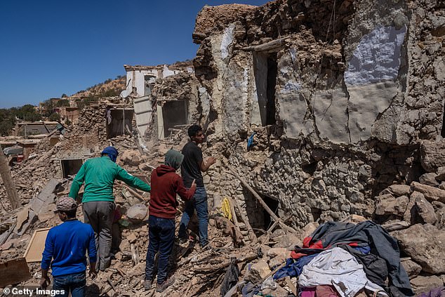 In the photo: Men search a destroyed building in Douzrou on Monday