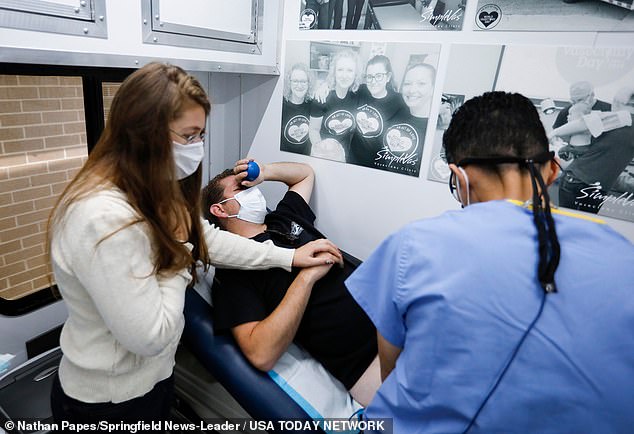 Erika Haas holds her friend Brad Bashor's hand as Dr. Esgar Guarin performs a vasectomy on Mr. Bashor in his mobile vasectomy on Friday, November 4, 2022