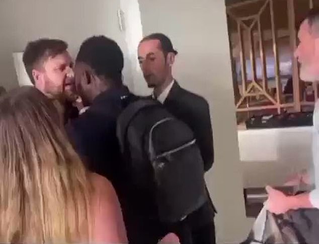 Footage circulating on social media shows Keane's colleague Micah Richards (centre, carrying bag) struggling with a man who attempted to headbutt the Irishman (far right)