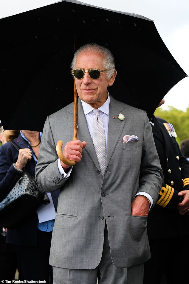 King Charles cut a cool figure with his umbrella and round frame sunglasses during the trip to HMS Iron Duke