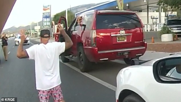 William Albrecht is seen out of his vehicle with his hands in the air as the officer points his gun at him on the busy New Mexico highway.