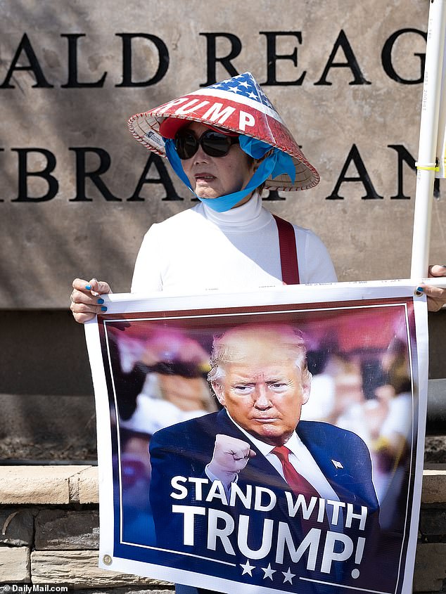 A Donald Trump fan is seen outside the Reagan National Library on Wednesday – despite Trump being 2,000 miles away