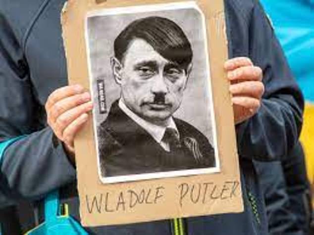 A protester holds a caricature of Putin, depicted with a combover and Hitler moustache