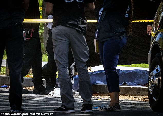 A body is covered in a tarp after a shooting in Washington DC in April.  Murder rates are on track to reach levels not seen in two decades