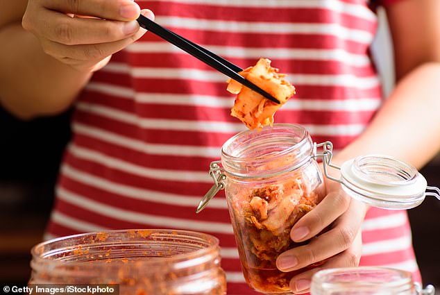 The image shows someone using chopsticks to remove kimchi from a jar.  Kombucha, kimchi and sauerkraut naturally contain probiotic bacteria that can help with your hangover