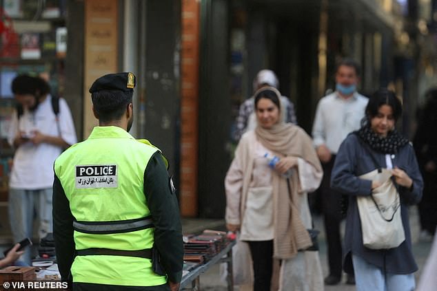 Women in Iran face up to 10 years in prison for not wearing a headscarf, under strict news laws soon to be passed by the country's ruling theocracy.  Pictured: An Iranian police force stands on the streets during the revival of the vice squad in Tehran, Iran, July 16, 2023