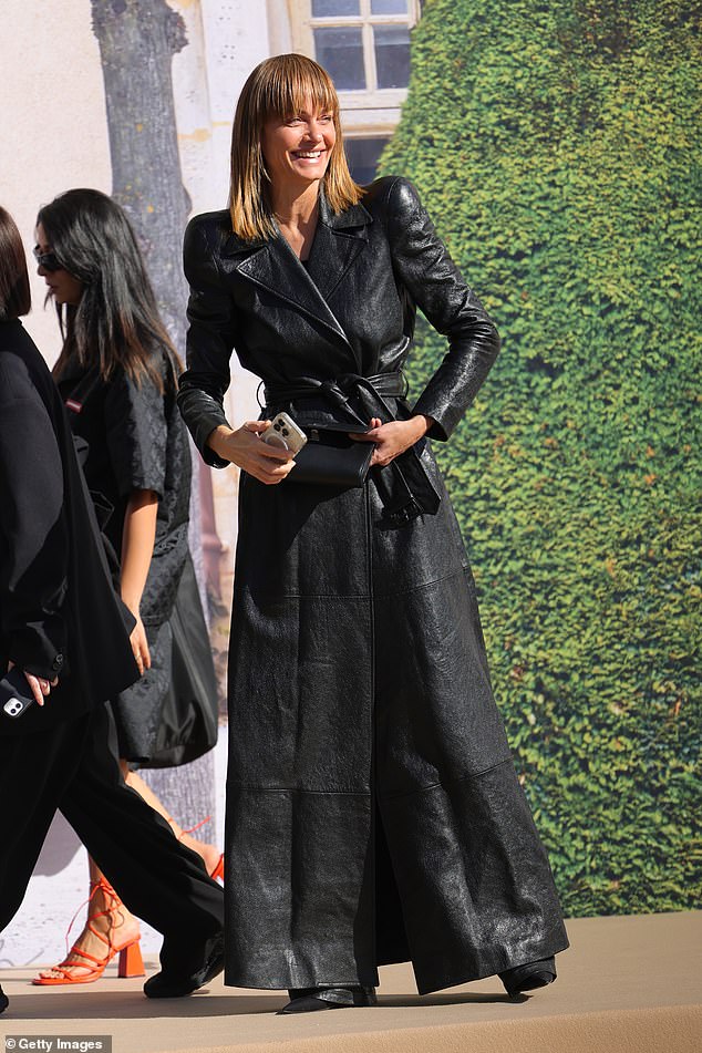 Beautiful: Amber Valletta wowed in a black trench coat with a belt that cinched around her waist