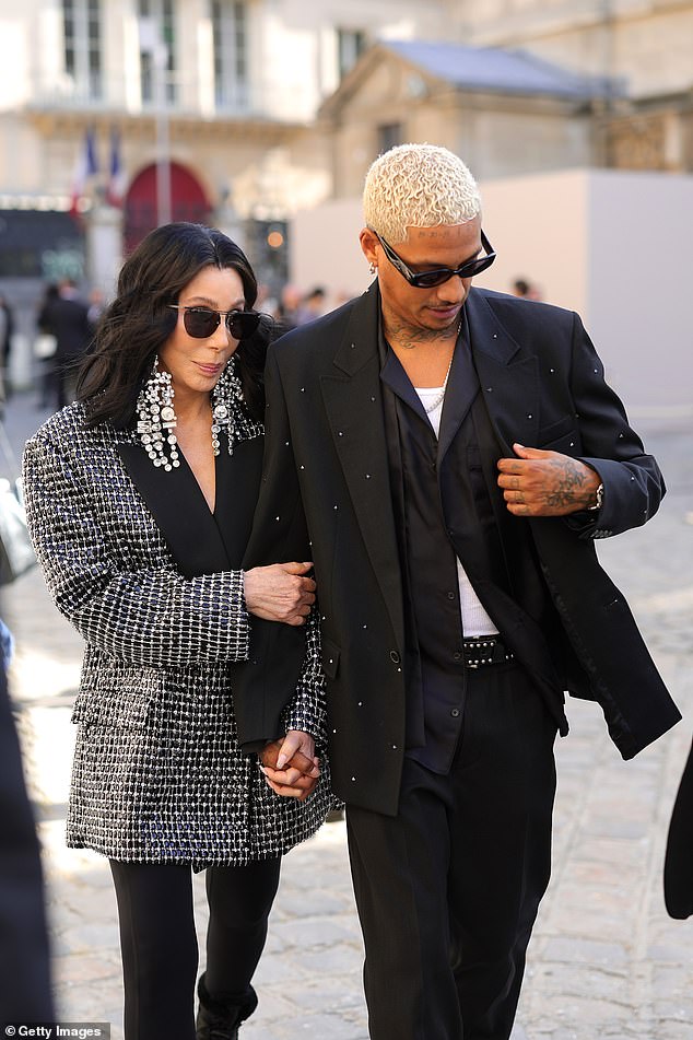 Looking good: Her music director wore a matching black blazer, paired with a satin shirt and stylish sunglasses