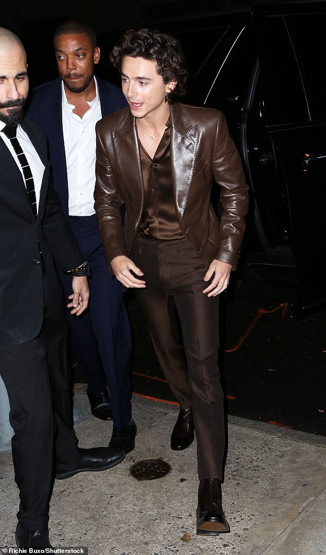 Fashion-forward: Continuing the monochrome look, he added pleated brown pants and shiny brown leather Chelsea boots