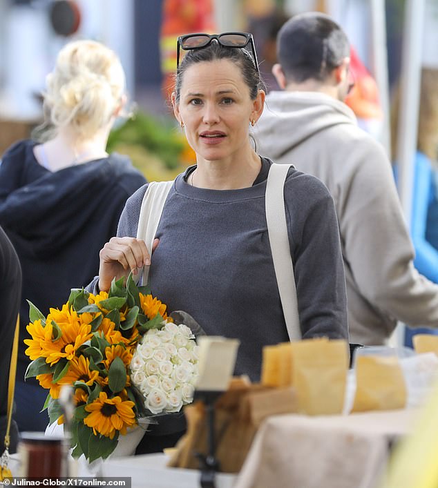 Athleisure attire: Jennifer - whose hair was pulled into a ponytail - was dressed for the gym in a gray sweatshirt, dark gray camouflage leggings and red sneakers