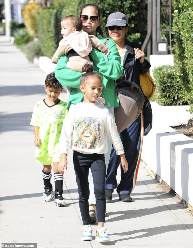 Striking: The 37-year-old social media personality cut a striking figure in a brightly colored outfit as she stepped out with her daughters Luna and Esti, seven and eight months, and her son Miles, five