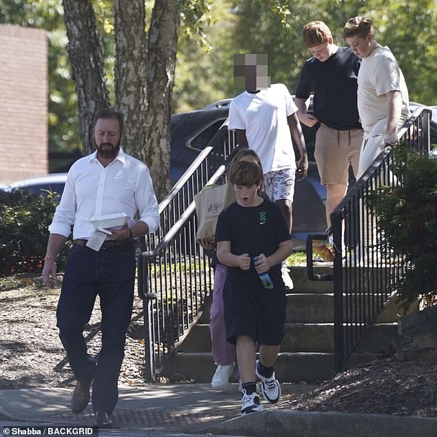 Family outing: The sports star looked serious as he strolled with his children