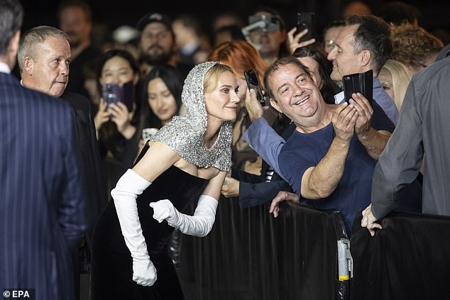 Greeting her audience: The German actress wore a chic black dress which she paired with a mirrored silver hooded headpiece that rested on her blonde hair and shoulders