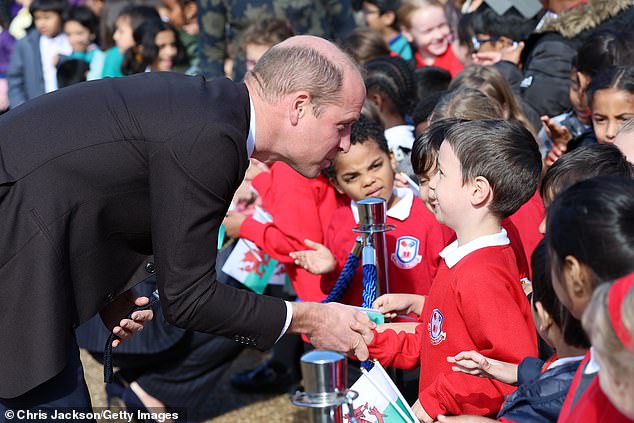 Prince William shook hands with a young student who looked sweet in his red school jumper and white polo shirt