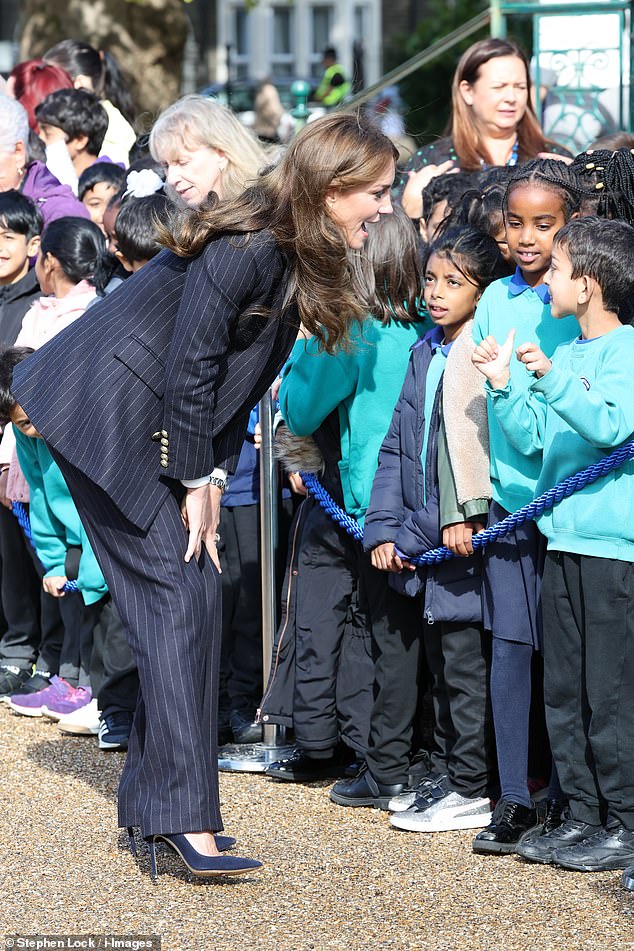 Kate, a mother of three, looked deep in conversation with the schoolchildren, who were bundled up in their coats and uniforms