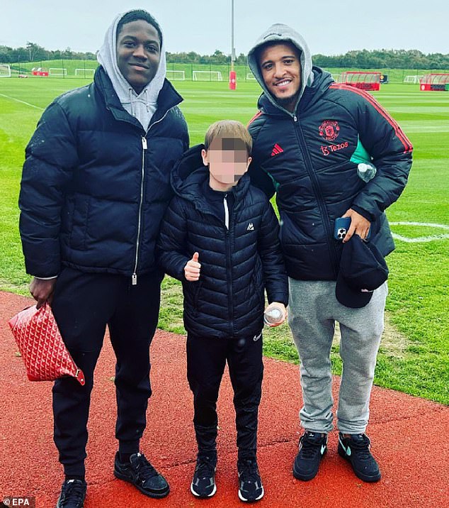 Sancho (right) was spotted in Carrington for the first time since the feud with Ten Hag after posing for a photo with Kobbie Mainoo (left) and a fan (Credit: Instagram @jacob_manunited)