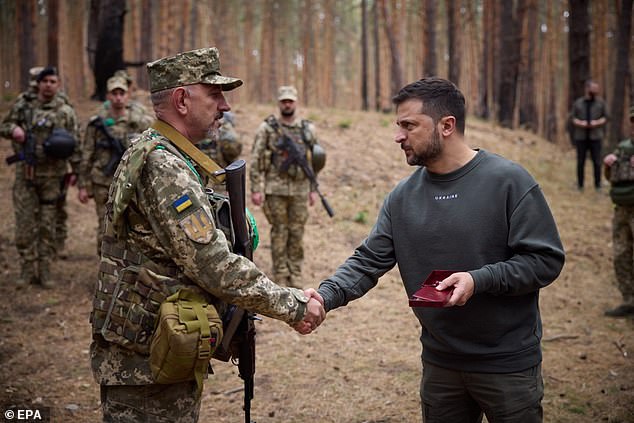 A photo made available by the Ukrainian Presidential Office shows President Volodymyr Zelensky (R) rewarding Ukrainian soldiers during his visit to military positions on the front line between Lyman and Kupiansk, October 3, 2023. Ukraine continues to try to repel Russian forces after their military mission in February.  2022 invasion