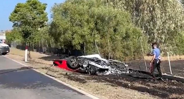 A police officer examines the damaged Ferrari after the fatal crash