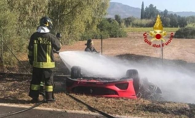 A firefighter sprays the Ferrari after the crash.  The Swiss tourists who died in the Ferrari were 63 and 67 years old