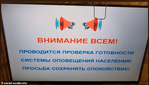 A message shown on TV and read over loudspeakers reads: 'Attention, everyone!  It is checked whether the warning system is ready for the population.  Please stay calm'