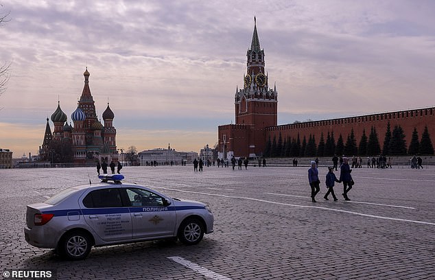 People walk past a police car on Red Square in the center of Moscow, Russia, March 20, 2023