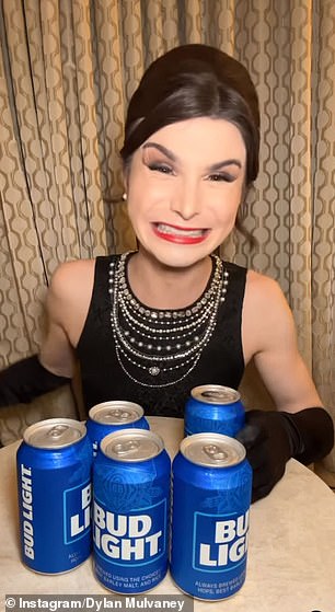 Dylan Mulvaney poses with Bud Light cans