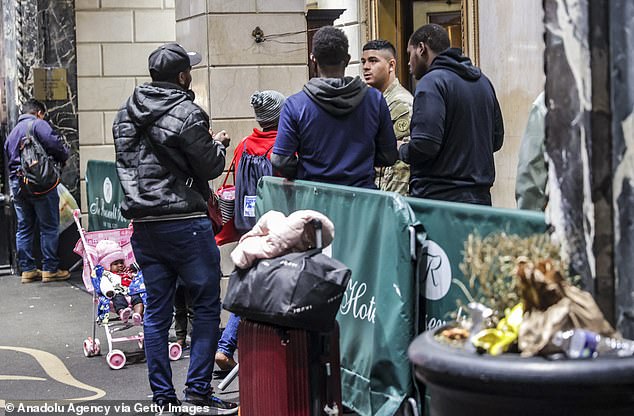 A group of migrants wait outside the Roosevelt Hotel in New York City, converted into a city-run shelter for newly arrived migrant families