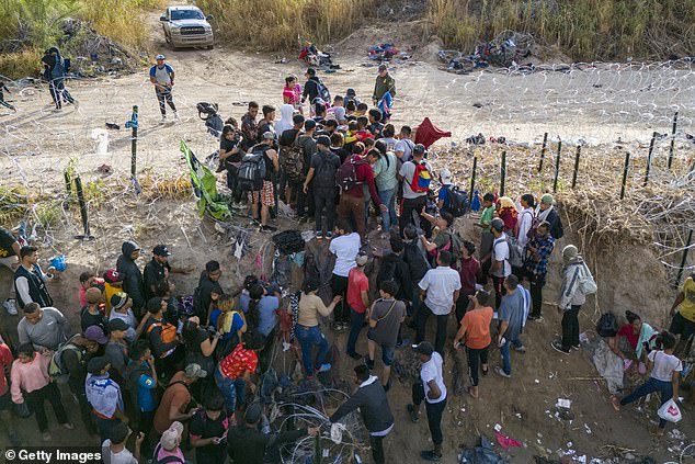 Seen from the air, a U.S. Border Patrol agent watches as immigrants walk into the United States after crossing the Rio Grande from Mexico