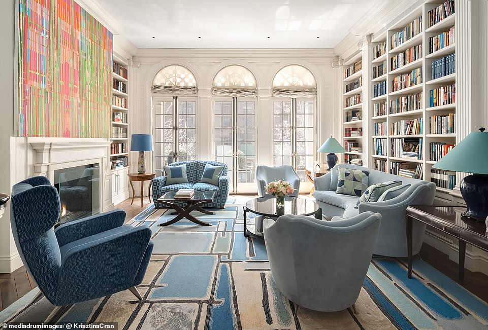 In the living room, built-in bookshelves line the walls, a trio of tall arched windows open onto the street, and two working fireplaces line the room.