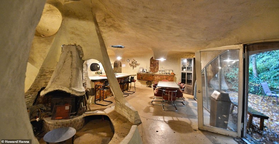 The living room has a seating area and a fireplace in a sunken well.  The dining room and kitchen can also be seen here