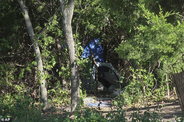 A tent sits in a bush in a wooded area amid businesses in Topeka, where the family reportedly lived