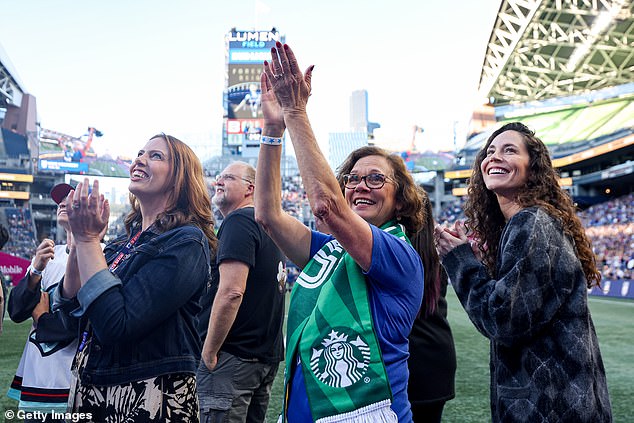 Rapinoe's mother, Denise (center), and her partner, Sue Bird (right), applaud fans before Friday's match