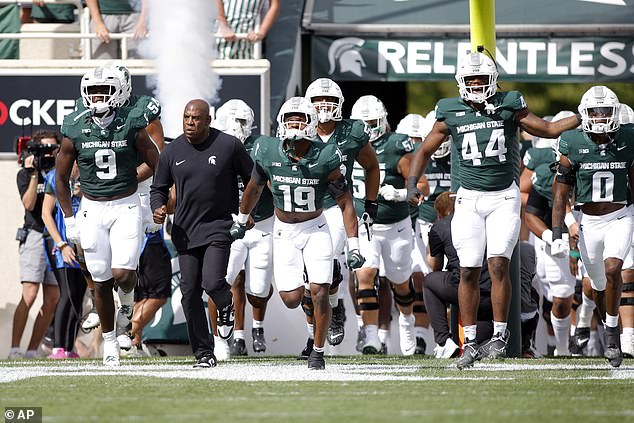 Michigan State coach Mel Tucker, in black, leads his team onto the field before their opener