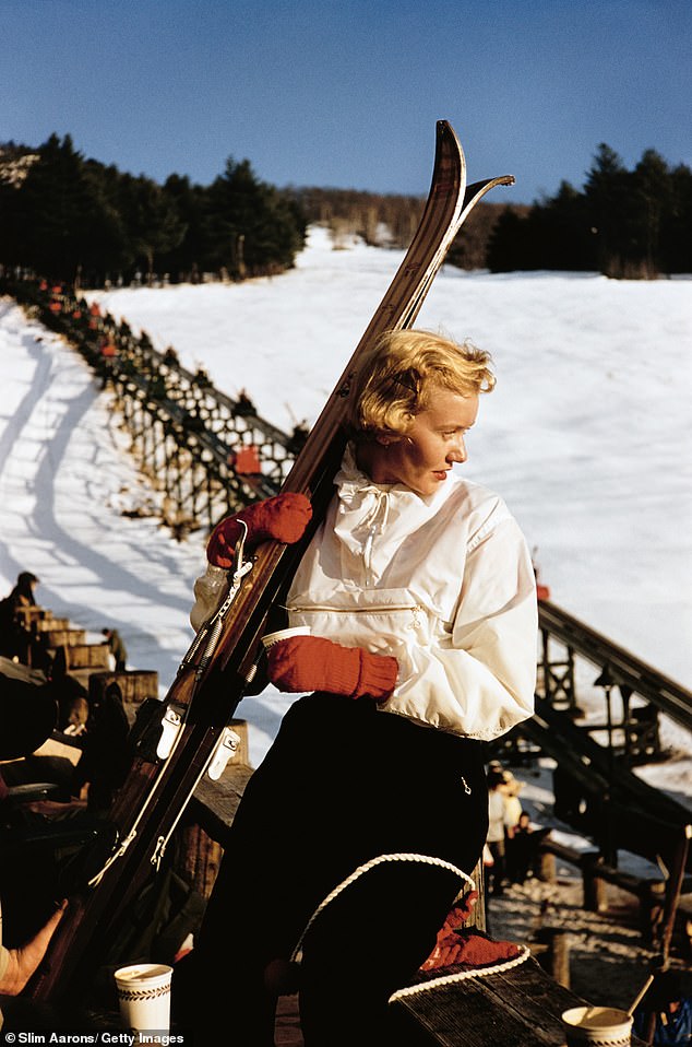 North Conway, New Hampshire, a woman looks out at the snow while holding her skis