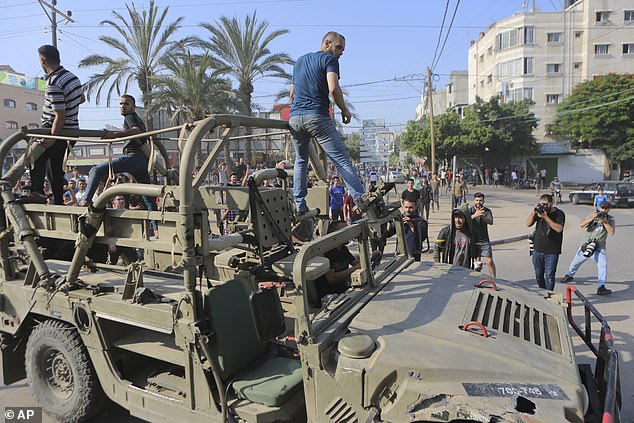 Palestinians ride an Israeli military vehicle taken by an army base overrun by Hamas militants near the Gaza Strip fence