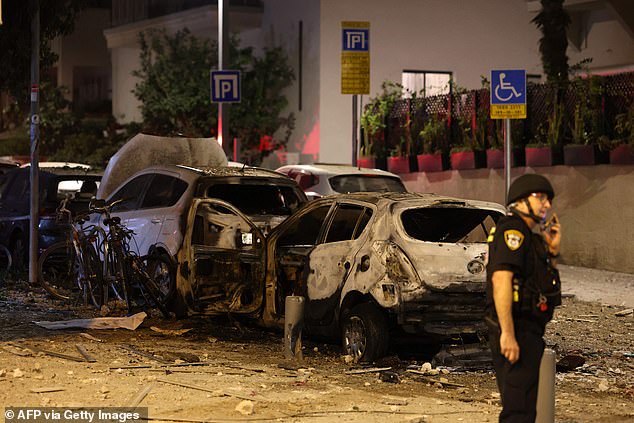 A member of the Israeli security forces stands next to a rubble-strewn street in Tel Aviv