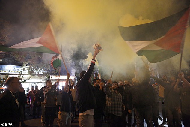 Iranian supporters of Hezbollah wave Palestinian flags during a celebration of attacks carried out by the militant group Hamas against Israel