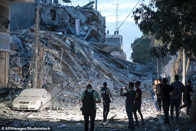 People walk on the ruins of a tower destroyed in an Israeli airstrike in Gaza City on Saturday