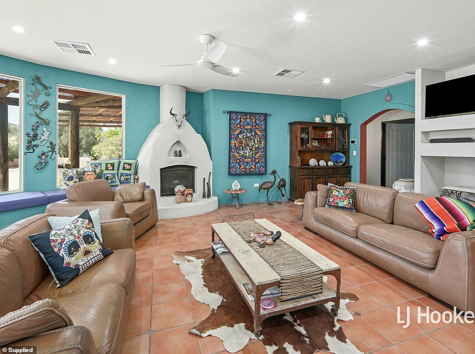 A semi-circular family room is the center of the home with an open kitchen, lounge and dining room with turquoise walls and a white Mexican-style fireplace