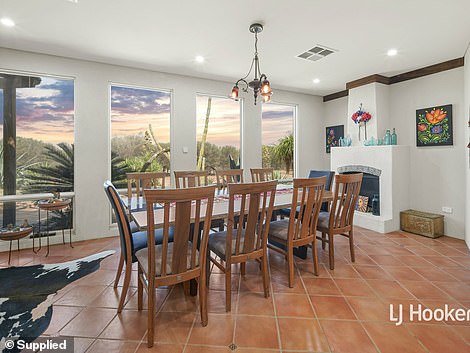 Upon entering the home, guests are greeted with high ceilings and cool terracotta tile flooring in the entryway, which flows into a formal dining area with views of the desert gardens beyond.