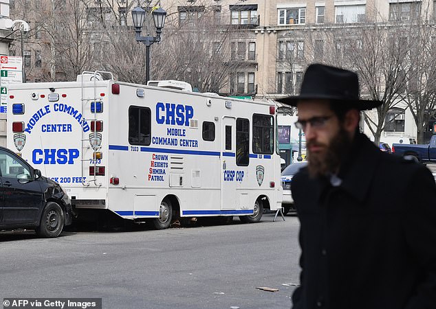 An Orthodox Jew walks past a 'Crown Heights Shmira Patrol' security vehicle in Brooklyn.  Although the unit looks like it's part of the NYPD, it's actually a local security patrol group