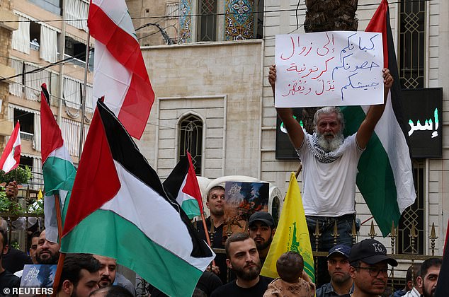 A man in Beirut was seen holding a placard that read: 'Your identity will disappear.  Your fortifications are made of cardboard.  Your army is humiliated and defeated'