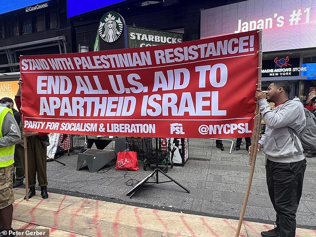 Two protesters hold up a sign in Times Square on Sunday